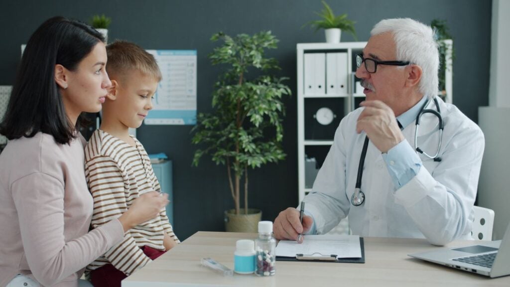 A doctor consulting with a mother and child in a modern clinic setting.
