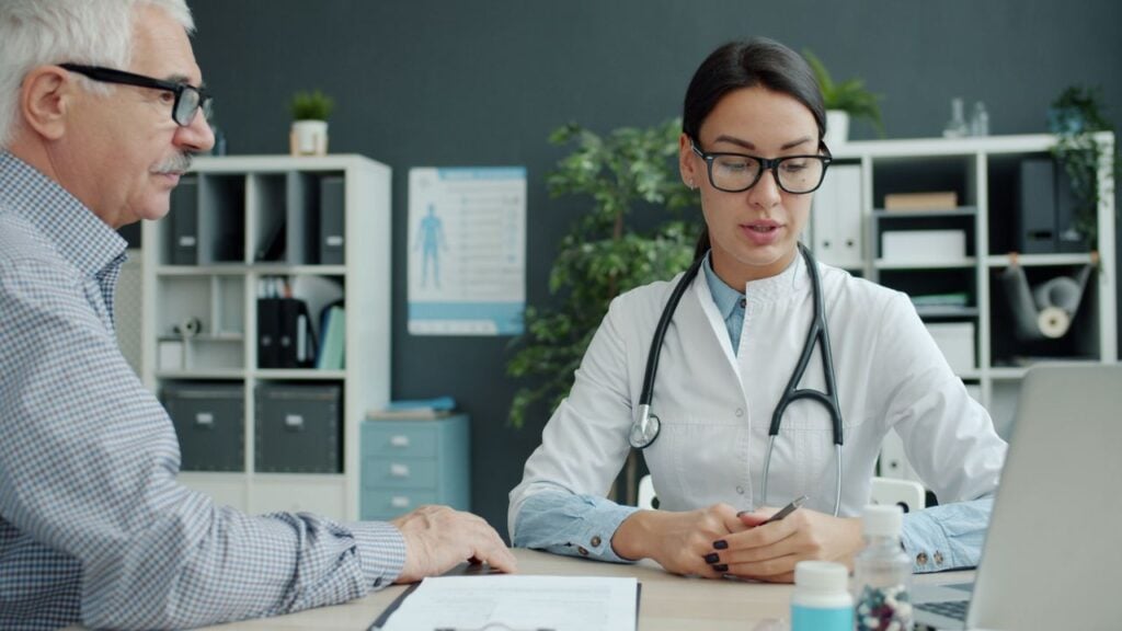 Medical professional discusses health with senior man in modern office setting.